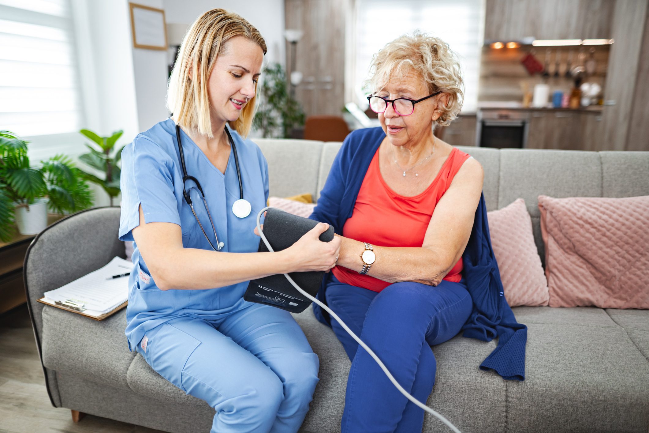 Young nurse measuring blood pressure of a senior woman during home visit